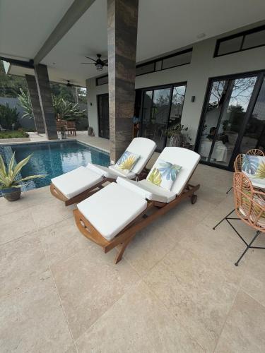 two lounge chairs sitting next to a swimming pool at Villa Montemar Ocean and Mountain Views Elevated 1200 FT with Wifi in Platanillo