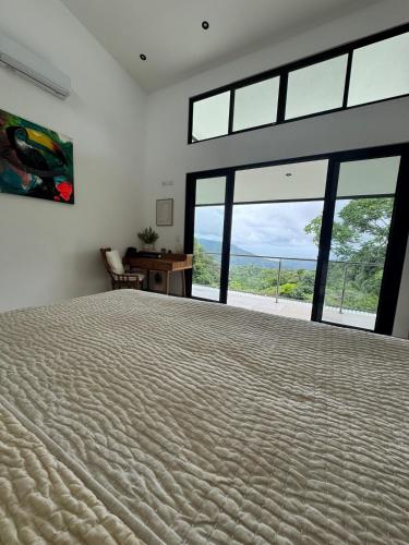 a bedroom with a large bed with a large window at Villa Montemar Ocean and Mountain Views Elevated 1200 FT with Wifi in Platanillo