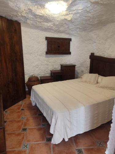 Un dormitorio con una cama blanca en una habitación. en Cueva del castillo de Chinchilla, en Chinchilla de Montearagón