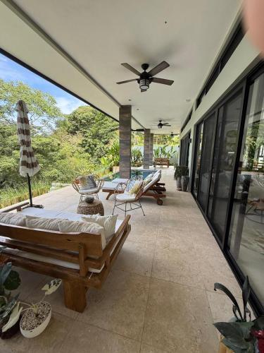 a screened in porch with a ceiling fan and chairs at Villa Montemar Ocean and Mountain Views Elevated 1200 FT with Wifi in Platanillo