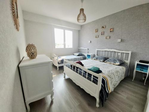 a bedroom with two beds and a nightstand and a bed sidx sidx sidx sidx at Appartement sur Port - 78m2 Balcon in Saint-Gilles-Croix-de-Vie