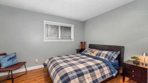 een slaapkamer met een bed, een stoel en een raam bij Knockan Hill Rentals - Ground Floor Suite in Victoria