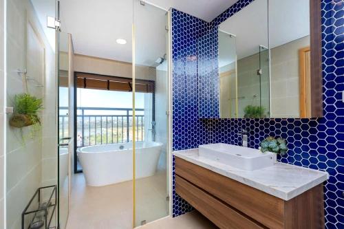 une salle de bain avec une baignoire, un lavabo et un miroir dans l'établissement Aria Vũng Tàu - Blue Sapphire Resort Căn Hộ, Biệt Thự Nghỉ Dưỡng Cách Biển 50m, à Xã Thắng Nhứt