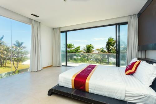 une chambre avec un grand lit et de grandes fenêtres dans l'établissement Aria Vũng Tàu - Blue Sapphire Resort Căn Hộ, Biệt Thự Nghỉ Dưỡng Cách Biển 50m, à Xã Thắng Nhứt