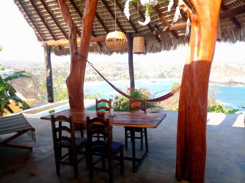 a wooden table and chairs in a porch with a hammock at Angelita's Nest House in Puerto Ángel