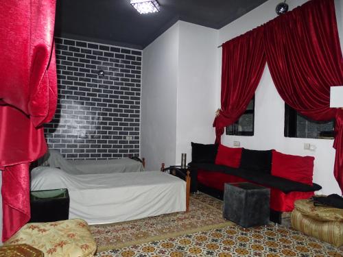 a bedroom with red curtains and a bed and a couch at Youth housing EL HABIB in Fès