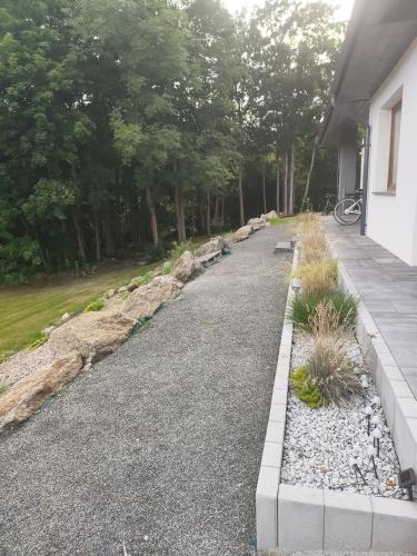 a driveway leading to a house with rocks and trees at Somewhere Between Apartments in Piechowice