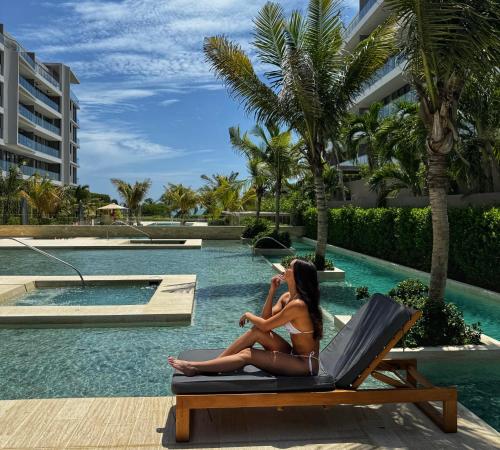 a woman sitting in a chair by the pool at a resort at Exclusivo loft - frente al mar in Cartagena de Indias