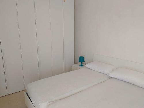 a white bedroom with a bed with a blue lamp on a night stand at Villetta a 100 MT dal mare via Nepole Torre Vado in Morciano di Leuca