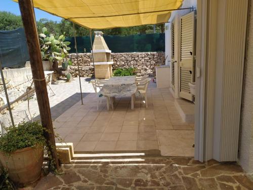 a patio with a table and a yellow umbrella at Villetta a 100 MT dal mare via Nepole Torre Vado in Morciano di Leuca
