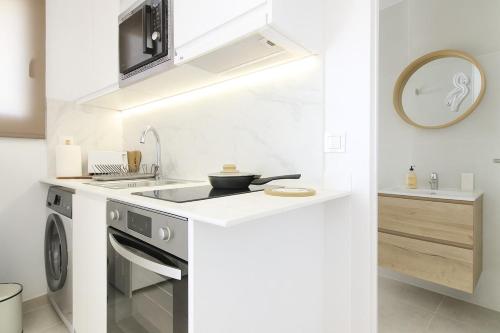 a white kitchen with a stove and a sink at RiuRau Home - Studio 50 meters from the beach in Calpe