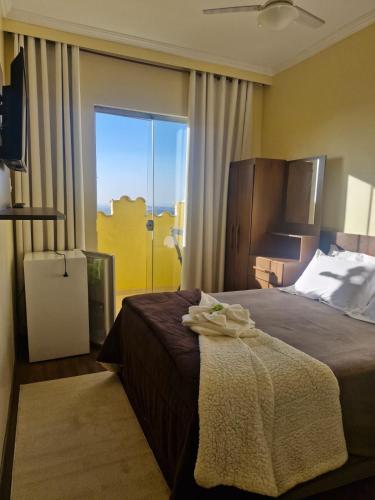 a bedroom with a bed and a large window at Pousada Reino Encantado - São Thomé das Letras - Minas Gerais in São Thomé das Letras