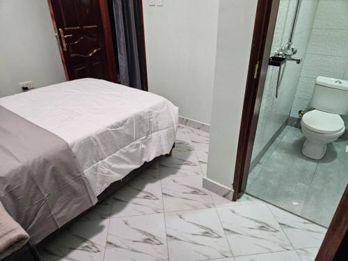 a bedroom with a bed and a shower and a toilet at SPea Apartment3 in Mbarara