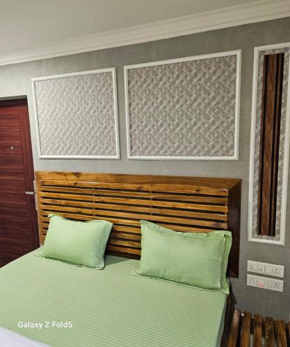 ein Schlafzimmer mit einem Bett mit zwei grünen Kissen in der Unterkunft Hotel Roxy GKR in Bhubaneshwar