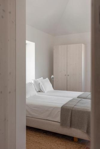 a white bedroom with a large bed with white walls at Dona Ana House in Tavira