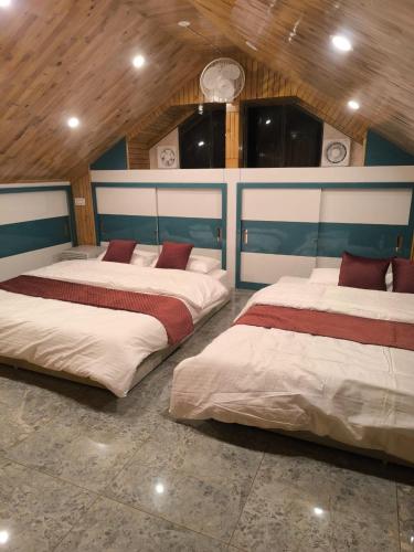 two beds in a large room with wooden ceilings at Tara Van in Dharamshala