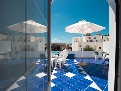 a patio with a table and chairs and an umbrella at Pension Ptolemeos in Fira