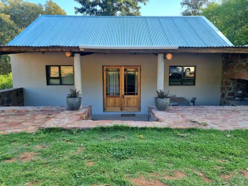 a small white house with a blue roof at Lambertshoek Farm Stay in Graafwater
