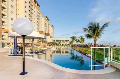 een zwembad in een resort met palmbomen en gebouwen bij Resort Varanda Salinas Park in Salinópolis