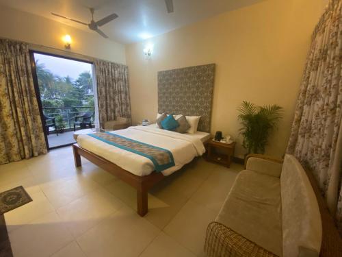 a bedroom with a bed and a couch and a window at River Raichak villa in Raichak