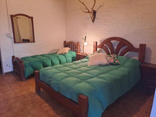 Una habitación con tres camas con sábanas verdes y un espejo. en Hostal Naico, en Naicó