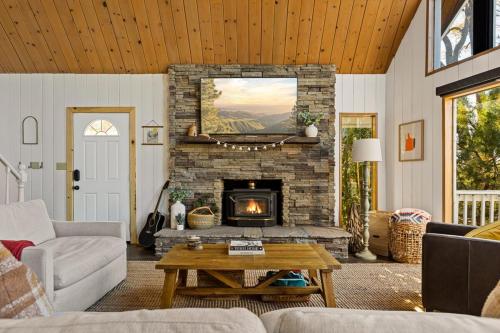 a living room with a stone fireplace with a tv at The Crown A-Frame Gated Central AC Lake Access in Lake Arrowhead