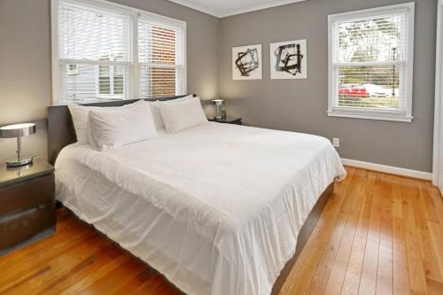 a large white bed in a bedroom with two windows at Cameron Village Modern Stylish Condo in Raleigh