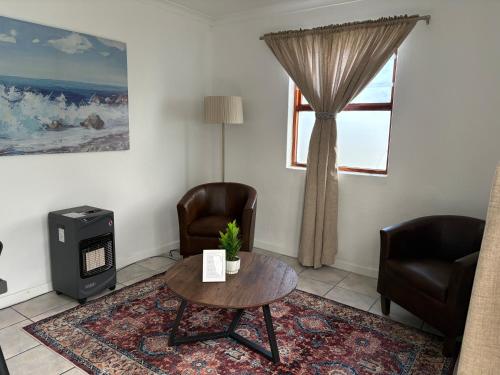 a living room with two chairs and a table and a window at Paterson Place Studios in Hermanus