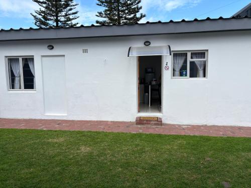 a white house with a door in a yard at Paterson Place Studios in Hermanus