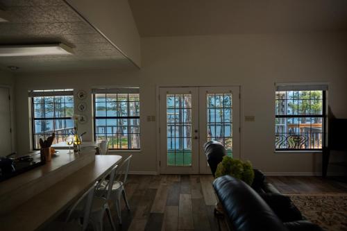 a living room with a table and chairs and windows at The Dock House in Mooringsport