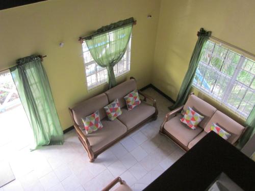 a living room with two chairs and two windows at Buttercup Cottage Apartments in Arnos Vale