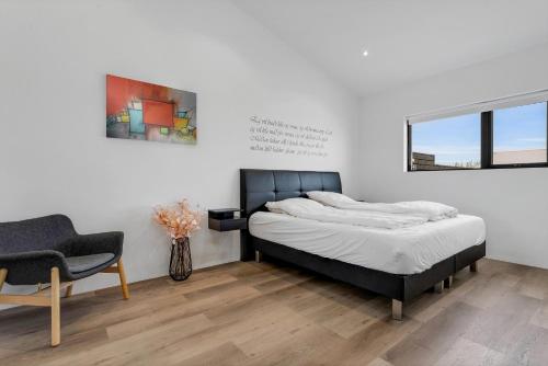 a bedroom with a bed and a chair and a window at The White House in Mosfellsbær