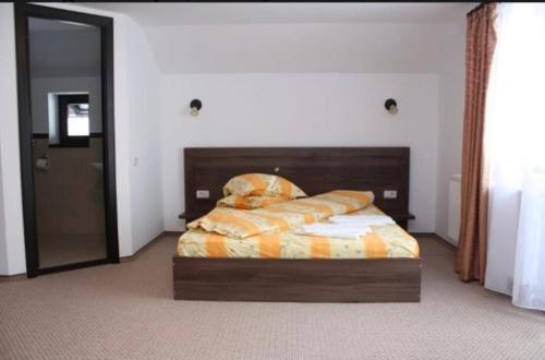 a bedroom with a bed with a wooden head board at Casa din Codru in Şimon