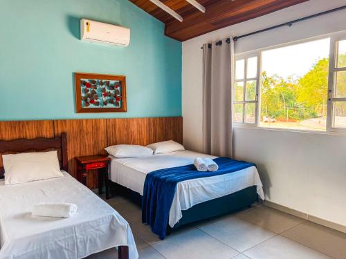 two beds in a room with blue walls and a window at Pousada Portal de Paraty- COM GERADOR DE ENERGIA in Paraty