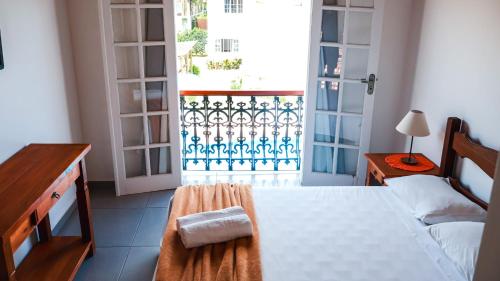 a bedroom with a bed and a door to a balcony at Pousada Portal de Paraty- COM GERADOR DE ENERGIA in Paraty