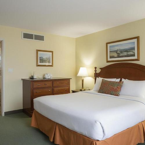 a bedroom with a large white bed and a dresser at Midtown Inn in Saskatoon