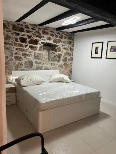 Cama blanca en habitación con pared de piedra en Bei Joschko, en Pakoštane
