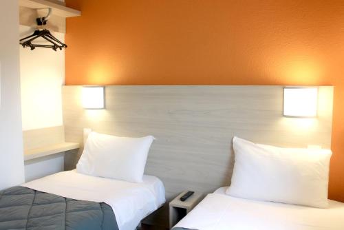 two beds in a hotel room with white pillows at Première Classe Plaisir Gatines in Plaisir