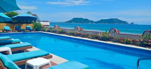 a swimming pool with chairs and the ocean in the background at La Paloma Oceanfront Retreat in San Patricio Melaque