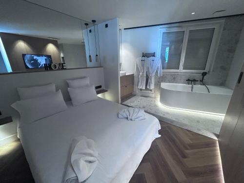 a bedroom with a large white bed and a bath tub at La Demi Lune in Tassin-la-Demi-Lune