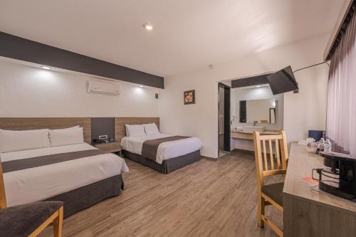 a hotel room with two beds and a television at Hotel Malibu in Guadalajara
