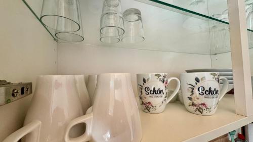 four white coffee mugs sitting on a shelf at Gemütliche Auszeit in Burg
