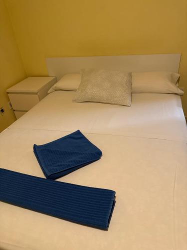 a white bed with two blue napkins on it at El Peine in Torrejón de Ardoz