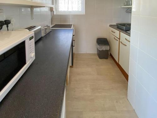 a kitchen with white counters and a black counter top at Sea Pearl in Kessingland