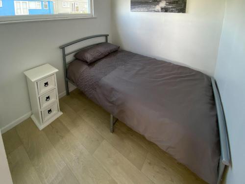 a bed in a small room with a night stand at Sea Pearl in Kessingland