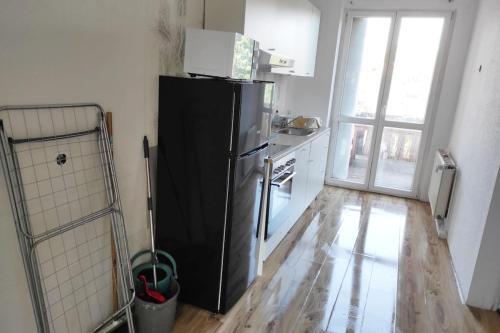 a kitchen with a black refrigerator and a wooden floor at Nice apartment with balcony & garden N1L in Zeitz