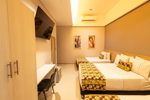 a hotel room with two beds and a tv at Hotel Santa Clara Boutique in Montería