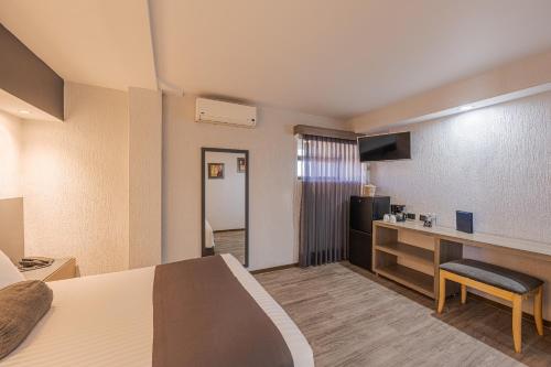 a hotel room with a bed a desk and a tv at Hotel Malibu in Guadalajara