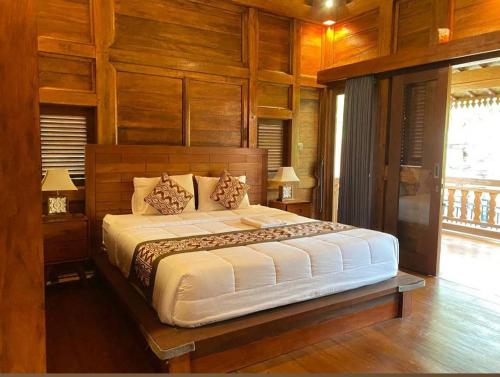 Un dormitorio con una cama grande con paredes de madera. en Chaplet House, en Ubud
