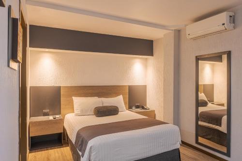 a hotel room with a bed and a mirror at Hotel Malibu in Guadalajara